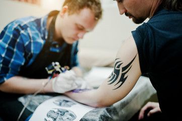Obraz na płótnie Canvas Tattoo master make tattoo for rocker man at tattoo salon