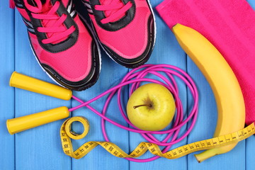 Pair of pink sport shoes, fresh fruits and accessories for fitness on blue boards