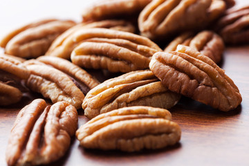 Pecans on wooden table extreme closeup with copy space. Shallow depth of field.