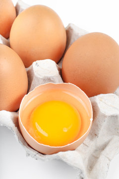 Whole and broken raw brown eggs in tray