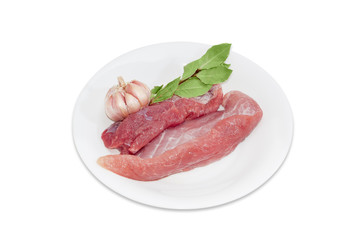 Uncooked pork, bay leaves and garlic on white dish