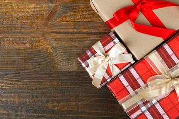 Fototapeta na wymiar beautiful gifts wrapped with festive ribbon on a brown wooden background