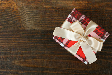 beautiful gift wrapped with festive ribbon on a brown wooden background
