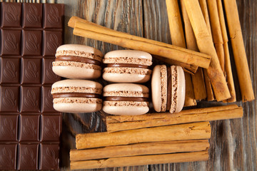 Chocolate macaroons and black chocolate on old wooden table