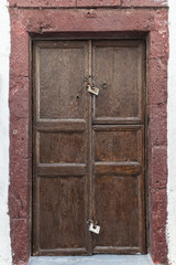 Brown door with red stones in Santorini