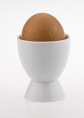 egg in white egg cup, isolated on white.