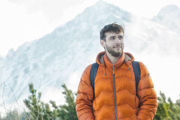 Cheerful mountaineer standing at astonishing winter high summits landscape background