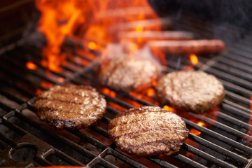 hamburgers en hotdogs koken op grill met vlammen