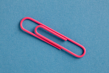 pink paperclip on blue background.
