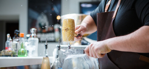 Bartender breaks ice with wooden hammer