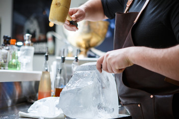 Bartender mannually crushed ice with wooden hammer and metal knife.