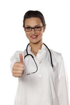 smiling young woman doctor showing thumbs up