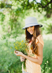 young beautiful brunette girl in a straw hat with red lips, beautiful smile and white teeth, posing in the Park t spring flowers in their hands, tenderness, happiness, mood, outdoor portrait, close up