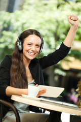 Young woman is using tablet and listening music in cafe.