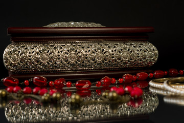 Wooden jewelry box with floral decorative elements and jewels on black background