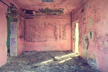 Old and abandoned pink room with bad rooftop and light coming through the door