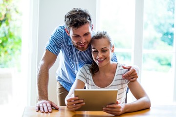 Smiling man and woman looking at digital tablet 