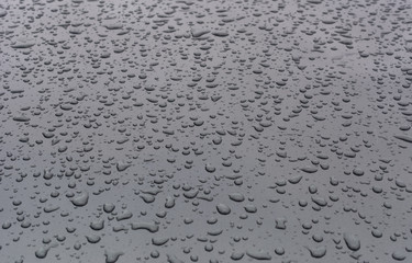 Numerous water drops on grey metal surface