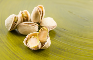Pistachios on green wooden background