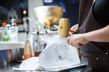 Bartender mannually crushed ice with wooden hammer and metal knife.