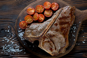Close-up of grilled T-bone beefsteak with tomatoes, above view