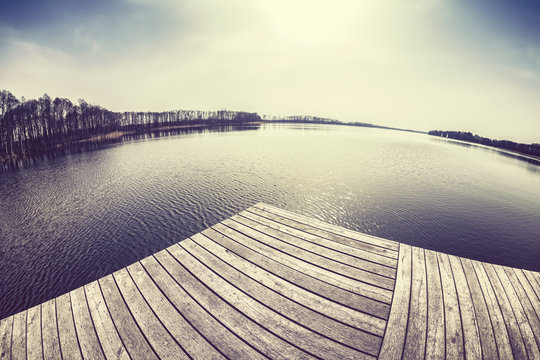 Old film stylized fisheye lens image of a wooden pier at sunset.