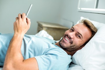 Obraz premium Happy man using mobile phone while lying on bed