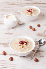 Oatmeal with milk, nuts and strawberry jam and milk jug