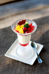 Fruit salad with jelly pudding in glass on wooden table