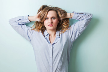 Naklejka premium Bright young blond girl is smiling and posing against the cyan wall