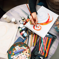 Painter paints a yellow and red colored sketch. Closeup of paint drawing process in art workplace....