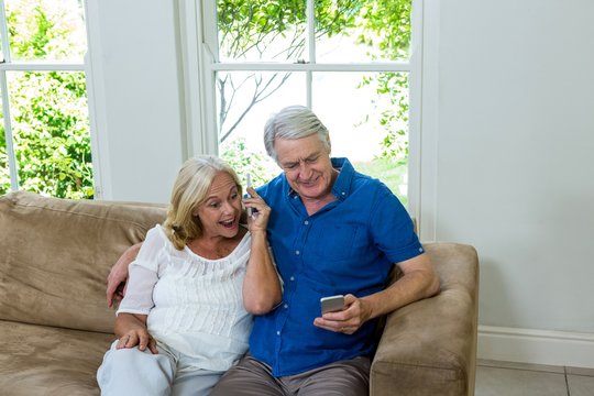 Surprised Senior Couple Looking At Mobile Phone At Home