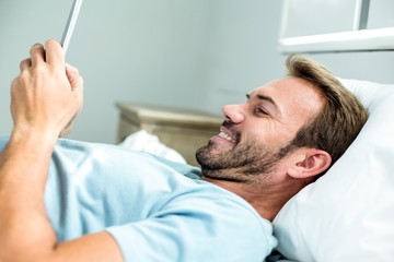 Man smiling while using cellphone on bed at home