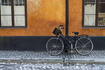 Fototapeta na wymiar Black bike with basket on red wall, Stockholm , Sweden