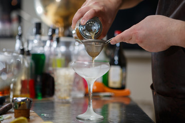 Bartender coocks cocktail behind a bar counter