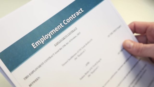 job applicant With Employment Contract In Hands. An employment contract is a kind of contract used in labour law to attribute rights and responsibilities between parties to a bargain.