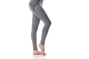 Close up side sexy view of woman legs stretching the muscles of the foot in gray sports thermal underwear with pattern.