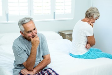 Sad senior man and woman sitting on bed