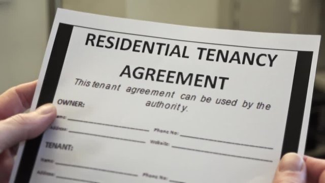 Male Hands Holds Residential Tenancy Agreement Form. Renting is an agreement where a payment is made for the temporary use of a good, service or property owned by another.