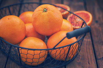 Fresh oranges in basket on a wooden table