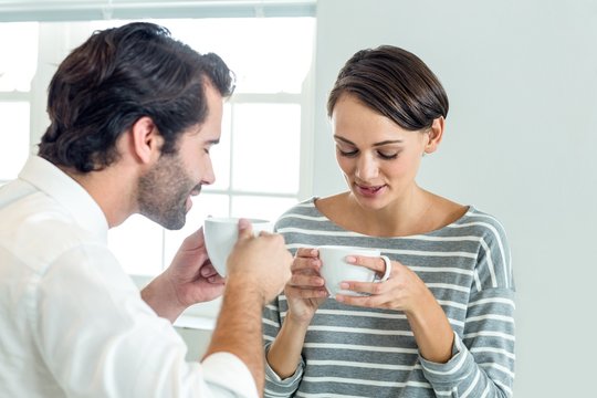 Businessman interacting with woman while drinking coffee
