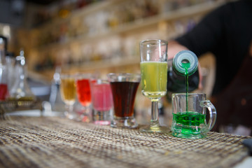 Obraz na płótnie Canvas Bartender pours various of alcohol drink into small glasses on bar