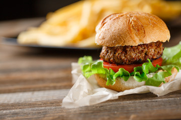 Homemade burger with french fries on wooden table