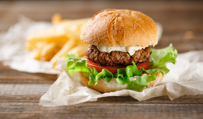 Homemade burger with french fries on wooden table