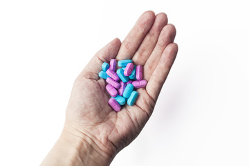 Heap of colorful pink and blue pills in white palm of woman hand from above