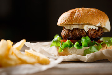 homemade burger and french fries on a wooden plate