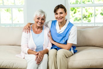 Portrait of smiling nurse with senior woman at home