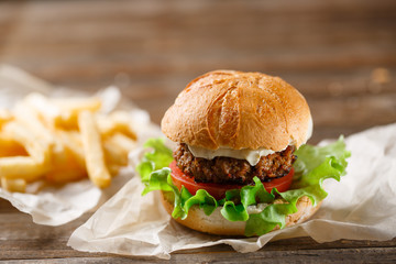 homemade burger and french fries on a wooden plate
