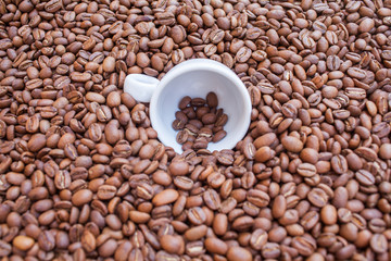Coffee mug in pile of coffee beans. Background.
