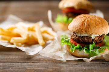 Homemade tasty burger and french fries on wooden table
